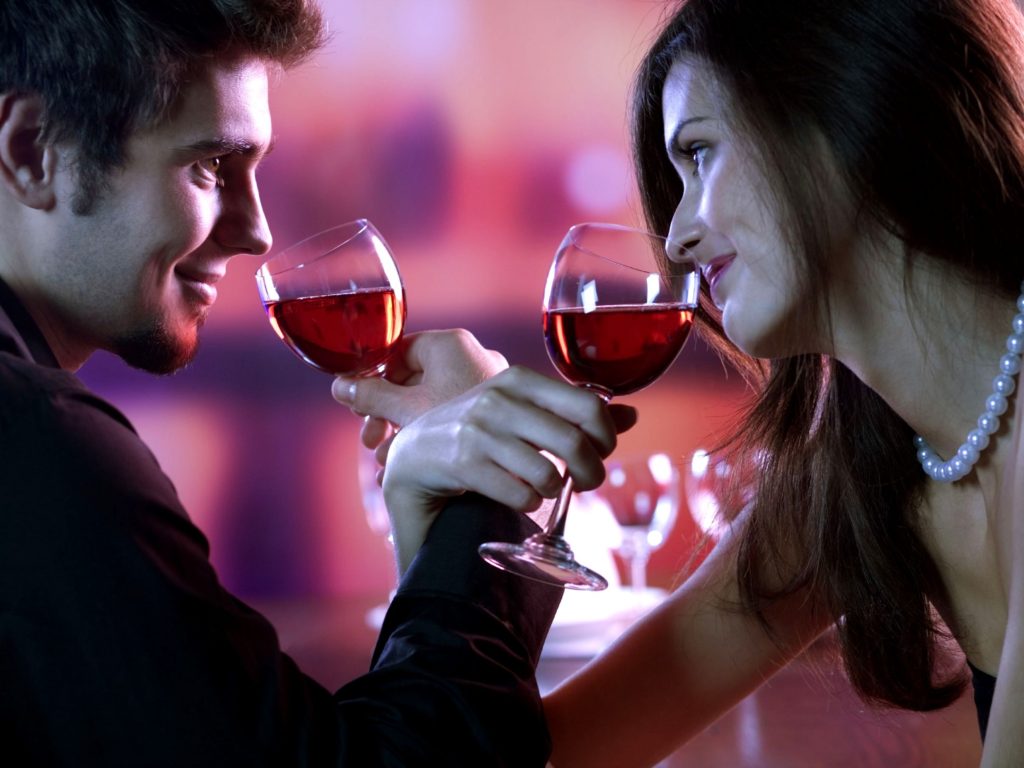 Young couple sharing a glass of red wine in restaurant, celebrating or on romantic date
