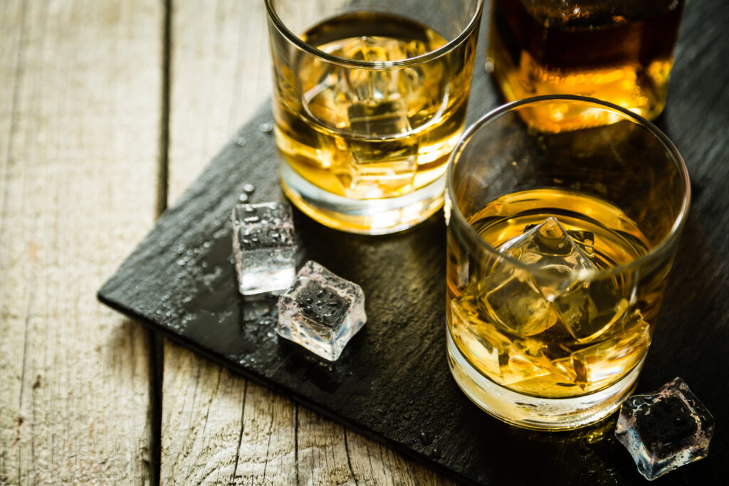 Szklanki z whisky na lodzie na desce.