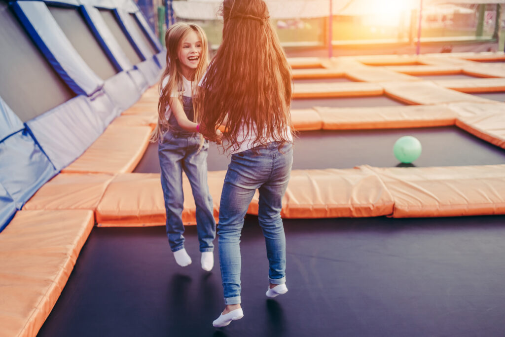 Dwie małe dziewczynki skaczące na trampolinie, park trampolin.