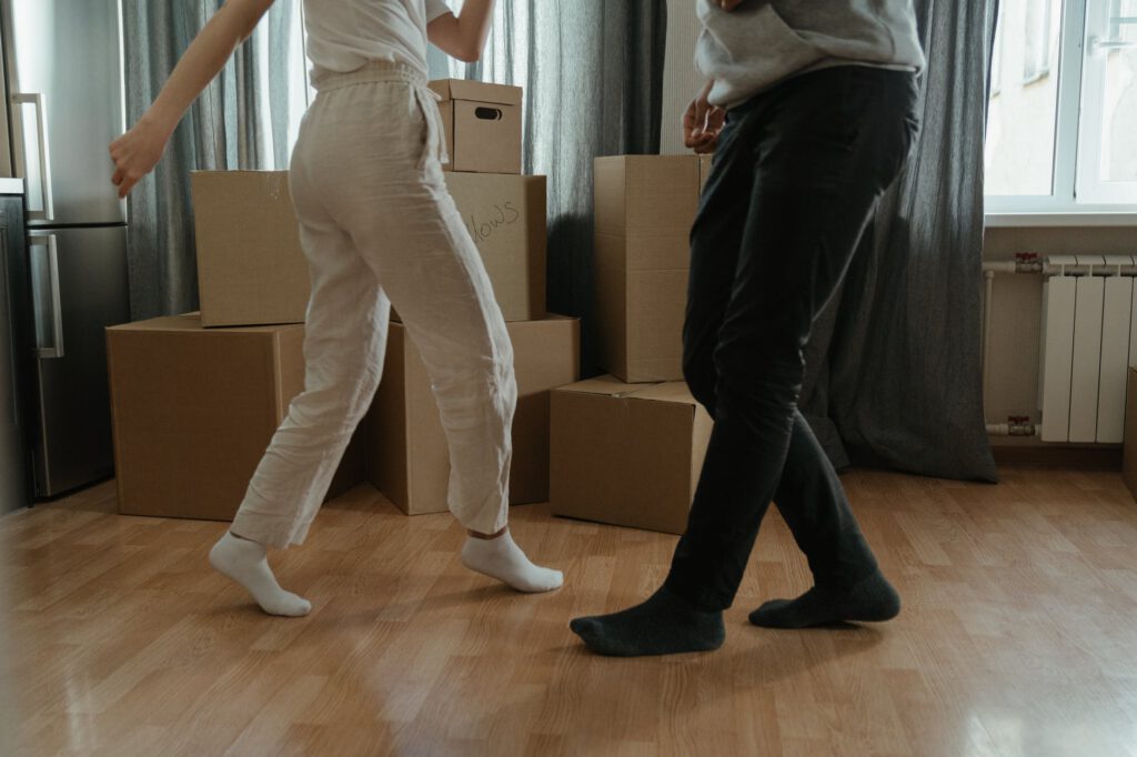Prezent na nowe mieszkanie - dwójka ludzi tańczy, w tle stoją pudełka