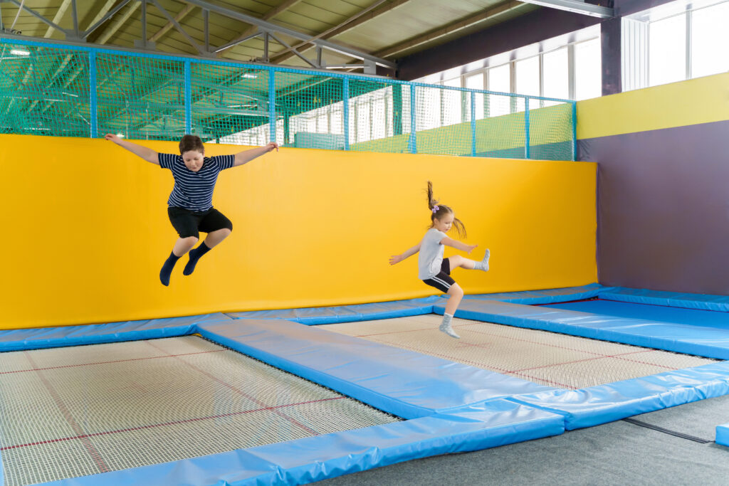 6 pomysłów na Dzień Dziecka: Happy smiling small kids jumping on indoors trampoline in entertainment center