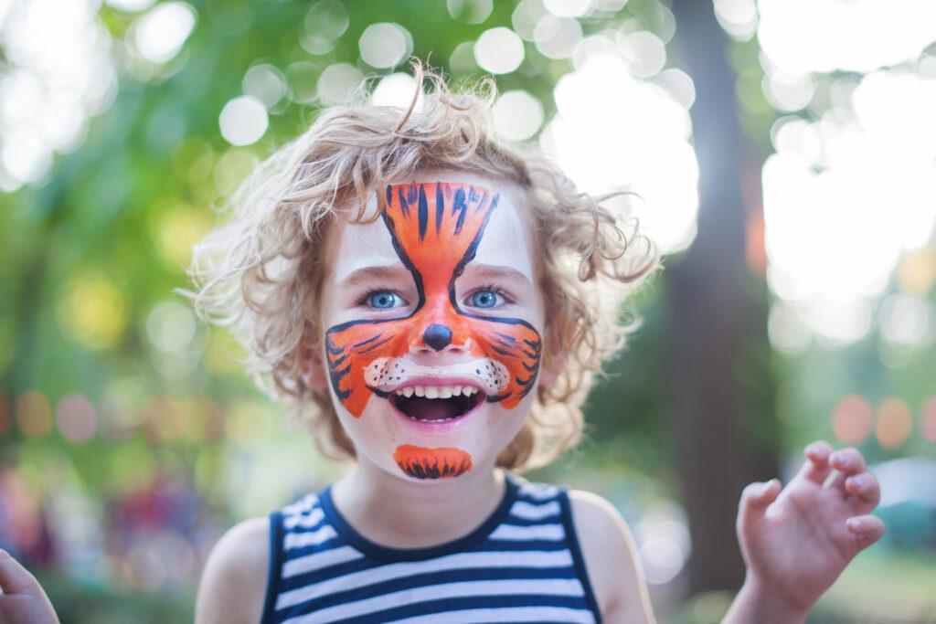Prezent na Dzień Dziecka dla 6 latka: uśmiechnięte dziecko z pomalowaną buzią udaje tygrysa