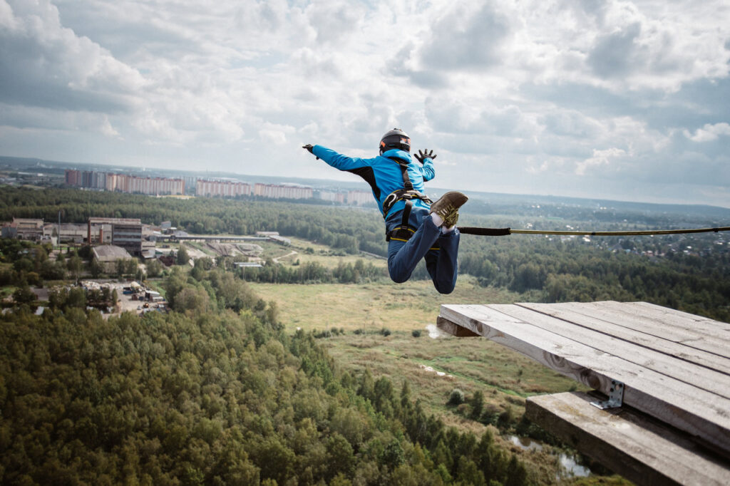 Pani skacząca podczas Dream Jump - uprząż na tułowiu, widok na miasto i zielone tereny