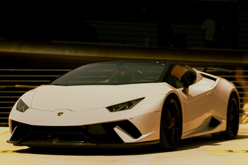 Biały samochód Lamborghini Aventador stoi na drodze. W tle brama.