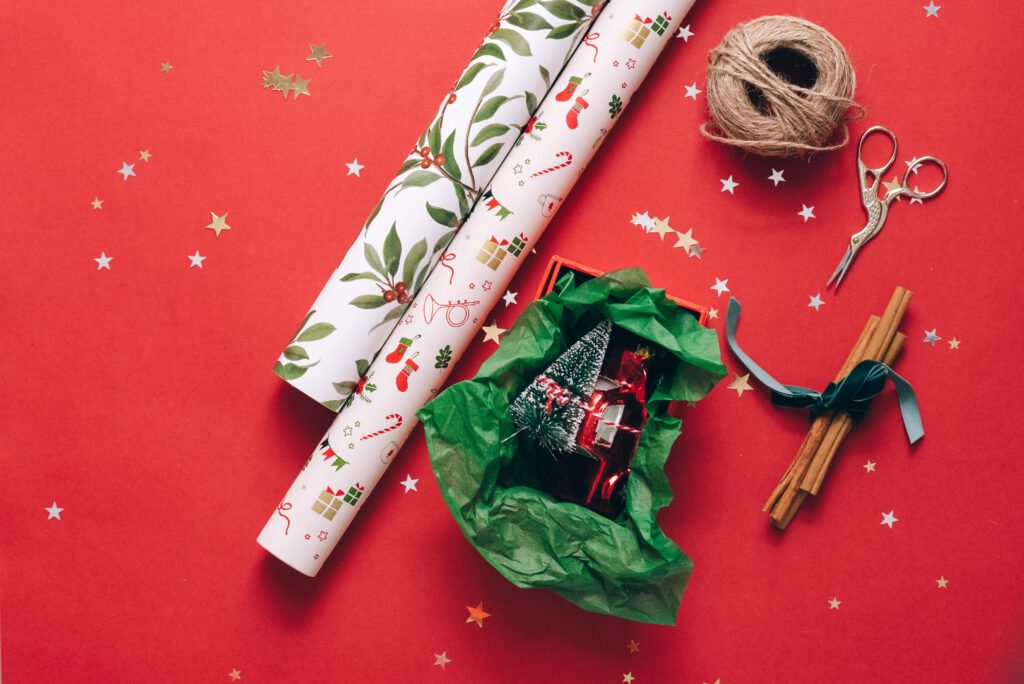 Zestaw do pakowania świątecznych prezentów. Nożyki, papier prezentowy, sznurek - na czerwonym tle.