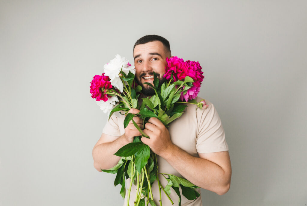 Mężczyzna trzyma białe i różowe kwiaty.
