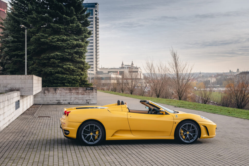 Jazda Ferrari - żółte Ferrari na parkingu, widok z boku